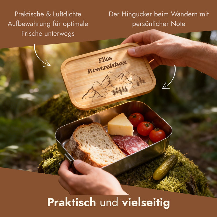 Personalisierte Edelstahl-Brotdose mit Bambusdeckel und Bergmotiv-Gravur, gefuellt mit Brotzeit in der Natur.