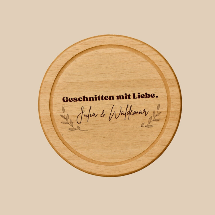 Rundes Schneidebrett aus Buche mit personalisierter Gravur und dekorativen Zweigen als Geschenkidee.