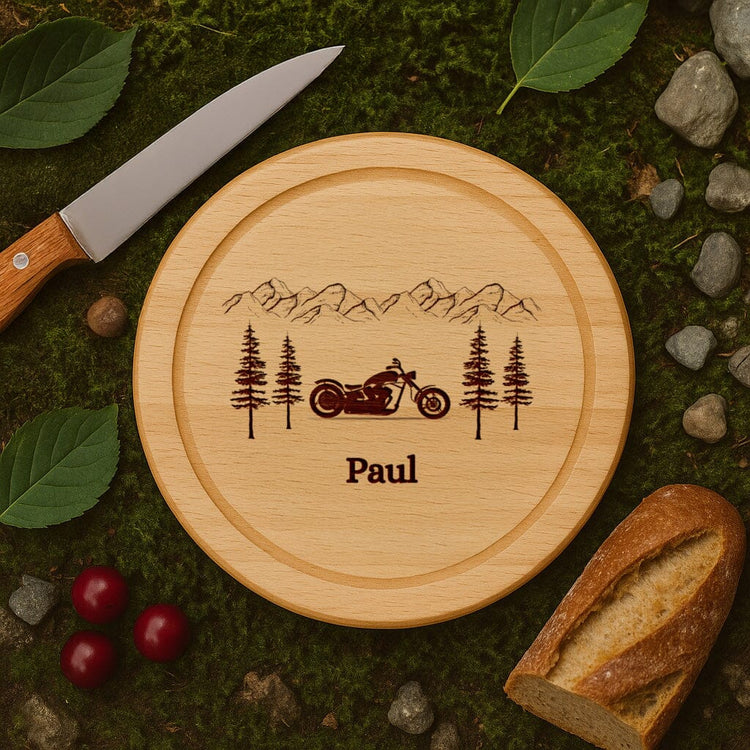 Rundes Schneidebrett aus Buche mit personalisierter Gravur eines Motorrads, Berglandschaft und dem Namen Paul.