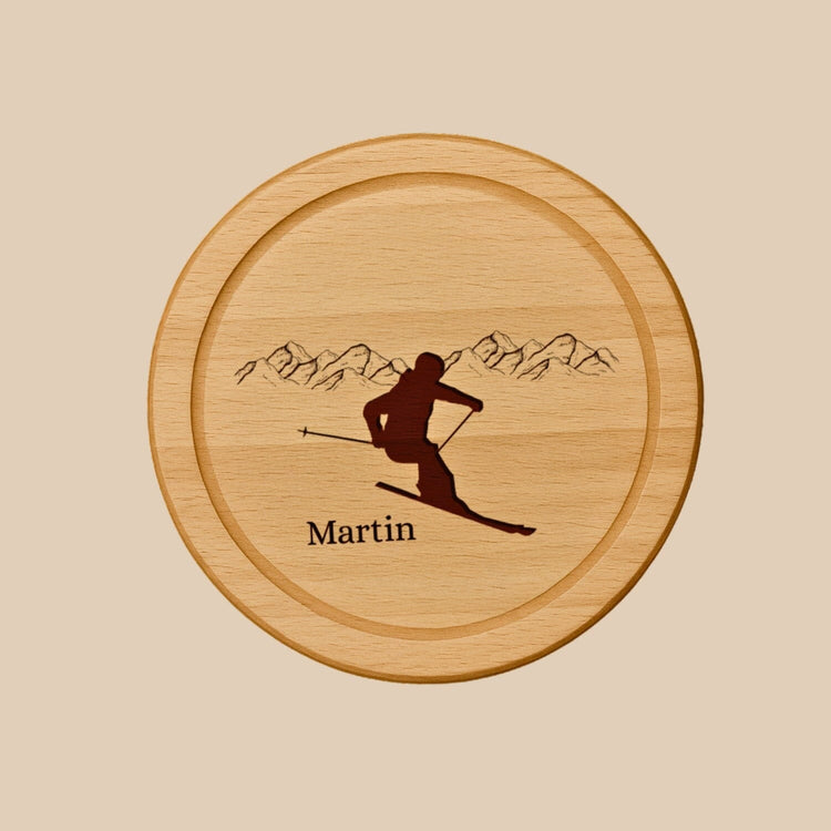 Rundes Holzbrett aus Buche mit personalisierter Gravur eines Skifahrers vor Bergpanorama und dem Namen Martin.