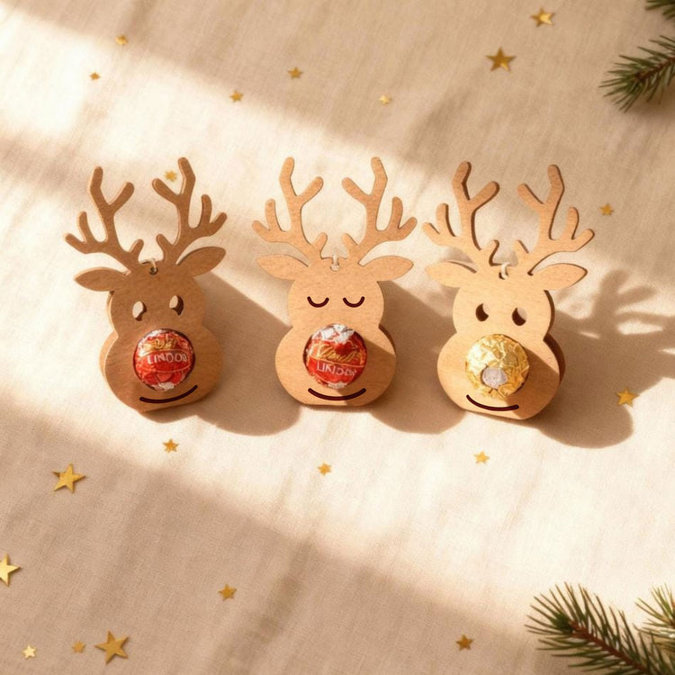 Drei Rentier-Schokoladenhalter aus Holz mit Lindor-Kugeln als weihnachtliche Geschenkidee.