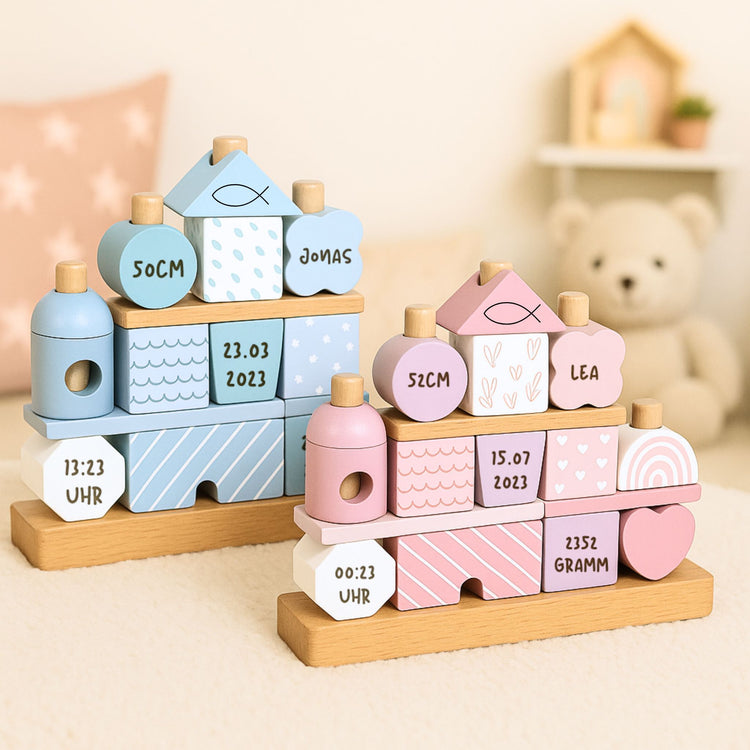Personalisiertes Stapelhaus aus Holz in Rosa und Blau mit gravierten Geburtsdaten wie Name, Datum und Groesse.