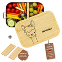 Personalisierte Edelstahl-Brotdose mit Bambusdeckel und Lama-Gravur, gefuellt mit frischem Obst und Gemuese.