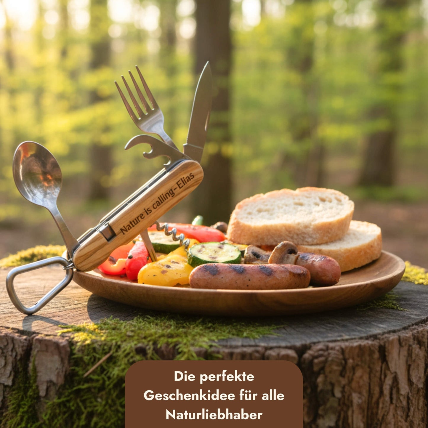 Campingbesteck-Set aus Edelstahl mit Olivenholzgriff und personalisierter Gravur auf einem Holzteller im Wald.