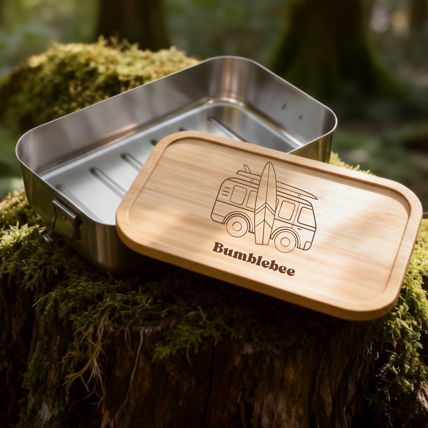 Personalisierte Edelstahl-Brotdose mit Bambusdeckel, Campervan-Gravur und Name auf moosigem Baumstumpf im Wald.