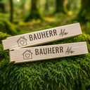Personalisierter Zollstock mit Bauherr-Gravur, Hausmotiv und individuellem Namen auf hellem Holz.
