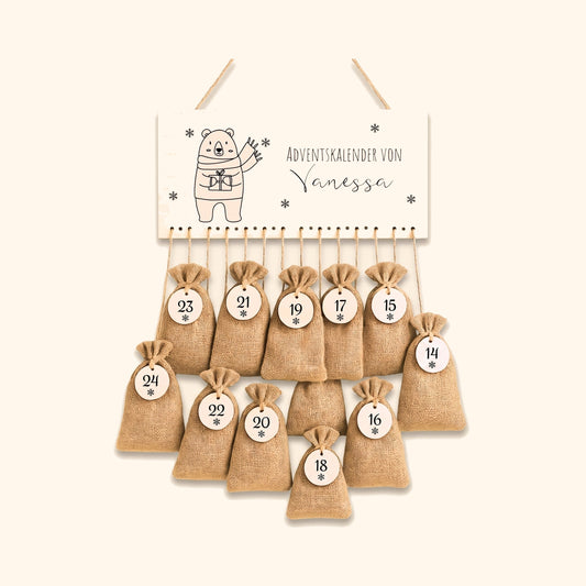 Personalisierter Adventskalender mit Jutesaeckchen und Namensschild vor cremefarbenem Hintergrund.