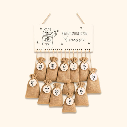 Personalisierter Adventskalender mit Jutesaeckchen und Namensschild vor cremefarbenem Hintergrund.