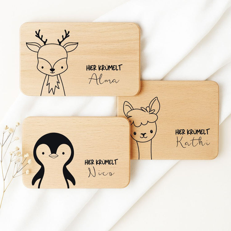 Personalisierte Frühstücksbrettchen aus Holz mit Tiermotiven Reh, Pinguin und Lama samt Namensgravur.