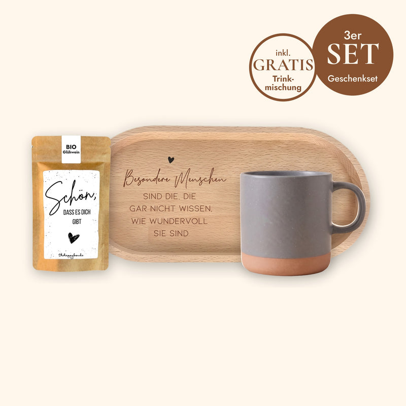 Geschenkset Kaffeepause: Keramiktasse Grau ohne Gravur, ovales Holz-Tablett aus Buche mit Spruch und Sprüche-Tütchen „Schön, dass es dich gibt“ vor cremefarbenem Hintergrund.