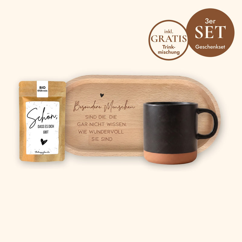 Geschenkset Kaffeepause: Keramiktasse Schwarz ohne Gravur, ovales Holz-Tablett aus Buche mit Spruch und Sprüche-Tütchen „Schön, dass es dich gibt“ vor cremefarbenem Hintergrund.