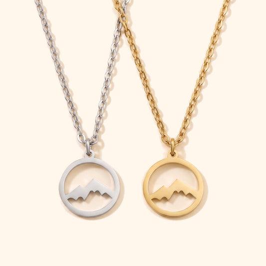 Halskette Berge aus Edelstahl in Silber und Gold nebeneinander, runde Anhänger mit Bergsilhouette, Packshot.