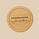 Rundes Schneidebrett aus Buche mit personalisierter Gravur und dekorativen Zweigen als Geschenkidee.
