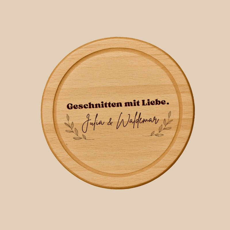 Rundes Schneidebrett aus Buche mit personalisierter Gravur und dekorativen Zweigen als Geschenkidee.