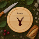 Rundes Schneidebrett aus Buche mit personalisierter Hirsch-Gravur und Name auf natuerlichem Moos-Hintergrund.
