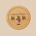 Rundes Holzbrett aus Buche mit personalisierter Gravur eines Holzfällers, Bergpanorama und dem Namen Jens.