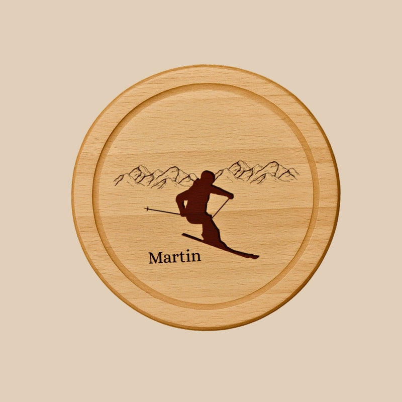 Rundes Holzbrett aus Buche mit personalisierter Gravur eines Skifahrers vor Bergpanorama und dem Namen Martin.