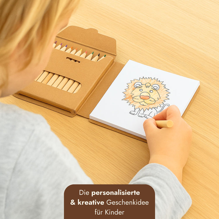 Kind malt Löwenmotiv in personalisierbarem Malbuch-Set mit 12 Buntstiften in brauner Kartonverpackung.