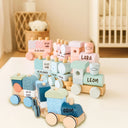 Personalisierte Holz-Stapelzuege mit gravierten Namen und Geburtsdaten in Pastell-Rosa, Mint und Blau.
