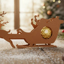 Weihnachtlicher Rentier-Schlitten aus Holz als Schokoladenhalter mit goldener Praline auf rustikalem Tisch.