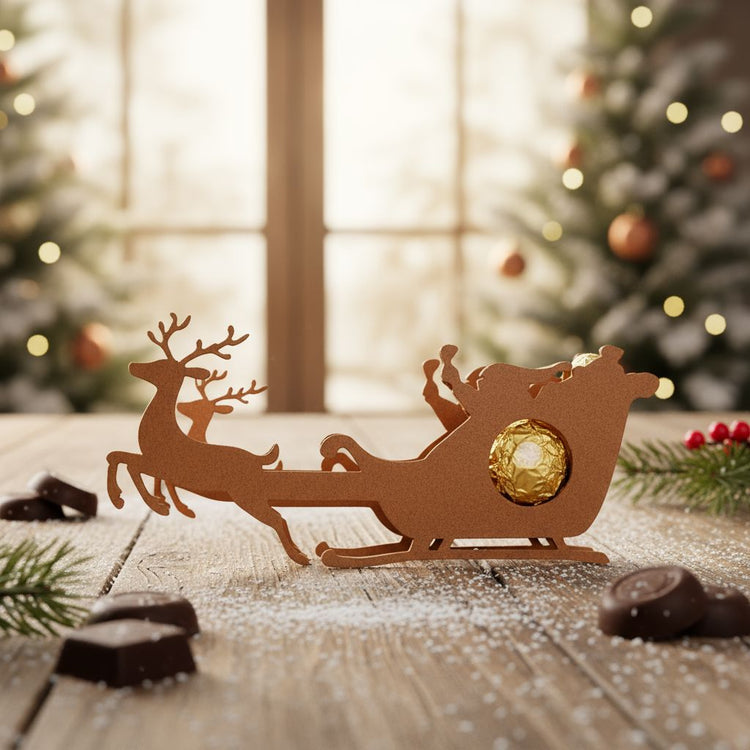 Rentier-Schlitten Schokoladenhalter aus Holz mit goldener Praline vor weihnachtlicher Dekoration.