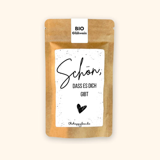 Sprüche-Tütchen aus Kraftpapier mit Etikett „Schön, dass es dich gibt“, Füllung BIO-Glühwein, vor cremefarbenem Hintergrund.