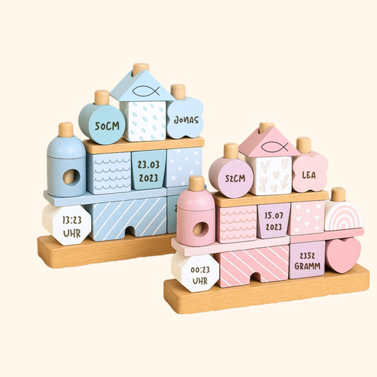 Stapelhaus Holz in Rosa und Blau mit gravierten Geburtsdaten, Packshot vor cremefarbenem Hintergrund