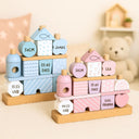 Personalisiertes Stapelhaus aus Holz in Rosa und Blau mit gravierten Geburtsdaten wie Name, Datum und Groesse.