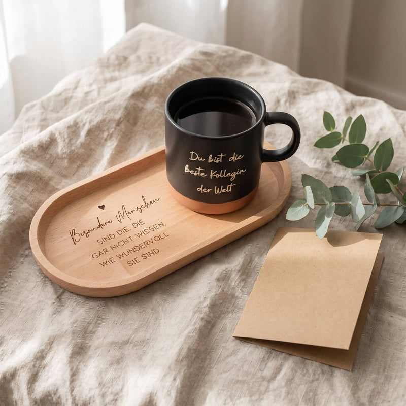 Graviertes Buchenholz-Tablett auf Leinen mit der schwarzen Happy Box Keramiktasse „Du bist die beste Kollegin der Welt“, Eukalyptus und Kraftpapier-Karte.
