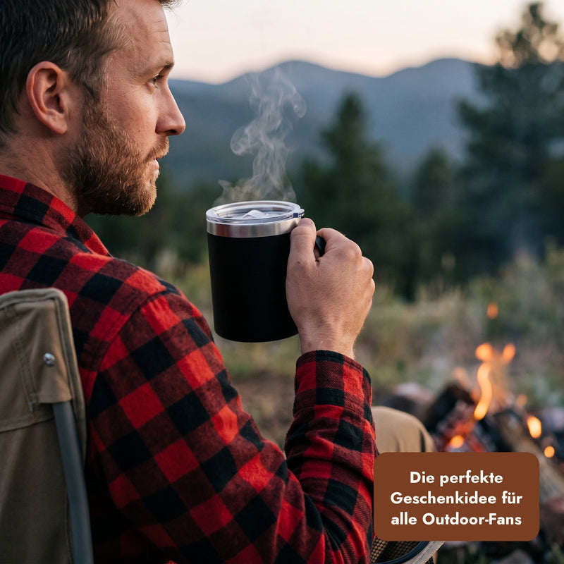 Mann mit schwarzem Thermobecher am Lagerfeuer, Text: Die perfekte Geschenkidee für alle Outdoor-Fans.