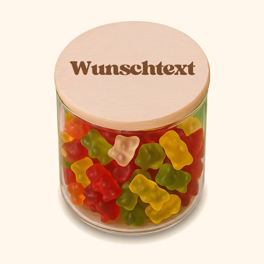Personalisiertes Vorratsglas mit graviertem Holzdeckel und Wunschtext, gefüllt mit bunten Gummibärchen. — vor cremefarbenem Hintergrund.