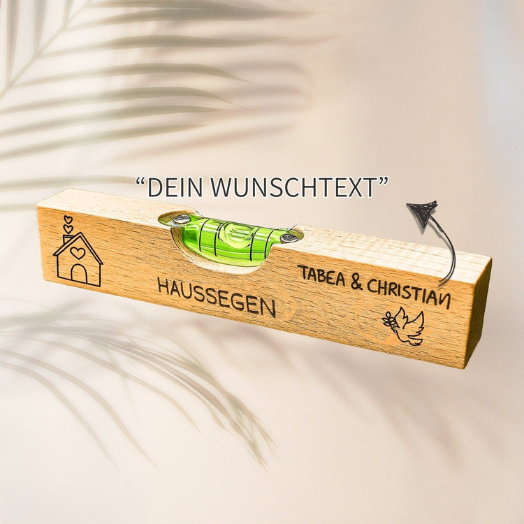 Personalisierte Wasserwaage aus Buchenholz mit Gravur von Namen, Haussegen-Motiv und Friedenstaube.