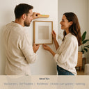 Paar haengt Bilderrahmen mit kleiner Wasserwaage aus Buchenholz an die Wand, ideal als personalisiertes Geschenk zum Richtfest.